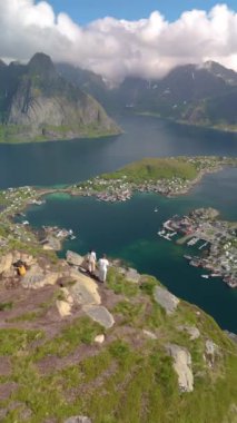 Reinebringen Lofoten Adaları 'nın tepesinde, Reinebringen' in tepesinde duran bir çift kadın ve erkek. Reine bakış açısına giden turistik yol, Reine, Lofoten, Norveç