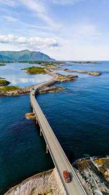 Norveç 'teki ikonik Atlantik Yolu' nun hava görüntüsü güneşli bir günde dolambaçlı köprüden geçen tek bir arabayı gösteriyor..