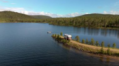 Huzurlu göl karavan parkı, deniz kenarında bir tekne ve yakınlardaki ormanlık tepeler manzaralı sakin güzellik, Laponya Finlandiya