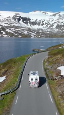 Karavan yolculuğu, karla kaplı dağların muhteşem manzarası, dingin bir göl ve güneşli gökyüzünün altında güzel bir otoyol. Langvatnet, Geiranger, Norveç