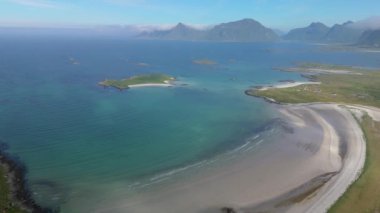 Turkuaz suları, uzak dağları olan sakin bir sahil manzarası huzurlu ve güzel bir manzara yaratıyor, Lofoten Norveç.
