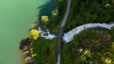 Yükselmiş bir manzara, yemyeşil bir göle açılan bir yol köprüsünü yakalar. Fjaerlandsfjorden, Fjord, Vestland, Norveç