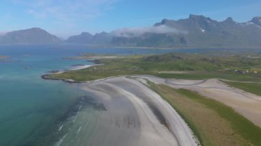 Dağlar, plajlar ve kristal berrak mavi sulardan oluşan muhteşem bir kıyı manzarası, Lofoten Norveç