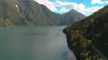 Sakin göl, ormanlar ve dağlarla çevrili mavi gökyüzünü yansıtır. Dokunulmamış doğa manzarası, Fjaerlandsfjorden, Fjord, Vestland, Norveç