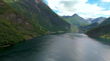 Bereketli yeşil dağlar ve açık mavi gökyüzü ile çevrili sakin bir gölün nefes kesici bir görüntüsü. Geiranger Fjord Norveç