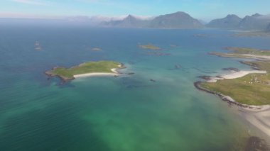 Yüksek açılı hava manzarası turkuaz sular ve yeşil adalarla çarpıcı bir kıyı manzarası sergiliyor. Lofoten Norveç