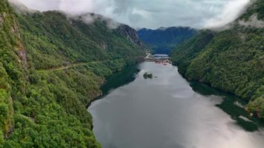 Görüntü, dağların ve ağaçların arasından geçen çarpıcı bir nehri yakalıyor. Norveç 'in Lovrafjorden kentinden sakin ve etkileyici bir doğal manzara sergiliyor.