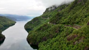 Norveç 'in nefes kesen güzelliğini havadan deneyimlemek, çarpıcı bir fiyortta dolambaçlı bir yol göstermek, yüksek dağlar ve yemyeşil ağaçlarla çevrili, Lovrafjorden, Norveç