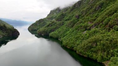 Sakin bir nehrin, gölün, dağların ve ağaçların çarpıcı bir klibi doğanın dingin güzelliğini zarif bir detayla yakalar. Huzurlu bir izleme deneyimi sunar: Lovrafjorden, Norveç