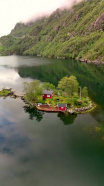 Huzurlu bir gölde, güzel kırmızı bir evi olan huzurlu bir ada manzarasının tadını çıkar. Rahatlama, doğa ve yalnızlık gibi konular için mükemmel, Lovrafjorden, Norveç