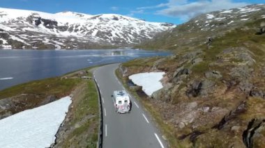 Karla kaplı gölün yakınındaki bir dağ yolunda Langvatnet, Geiranger ve Norveç 'i temsil eden bir kamp aracının hava görüntüsü.