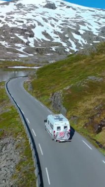 Karavanda, karla kaplı tepeler ve sakin göl manzaraları, Langvatnet, Geiranger, Norveç ile nefes kesici bir dağ manzarasının ortasında dolaşıyorlar.