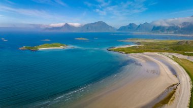 Yeşil yeşil adalarla Norveç 'in Lofoten Adaları' ndaki görkemli dağların arasına yerleştirilmiş el değmemiş beyaz kumsal manzarası. Kolbedeliden Sahili, Lofoten