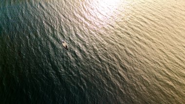 Küçük bir tekne, Finlandiya 'daki bir gölün dalgalı sularında batan güneşin sıcacık parıltısıyla yıkanır..