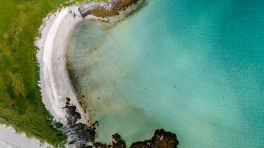 Norveç kıyı şeridi boyunca turkuaz bir koy şeklinde kıvrılan beyaz bir kumsal manzarası. Kolbedeliden Sahili, Lofoten Norveç
