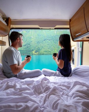 Bir çift, Norveç 'teki çarpıcı bir fiyorda karavanlarının camından dışarı bakarken sabah kahvelerinin tadını çıkarıyor. Lovatnet Gölü Lodal Vadisi Norveç