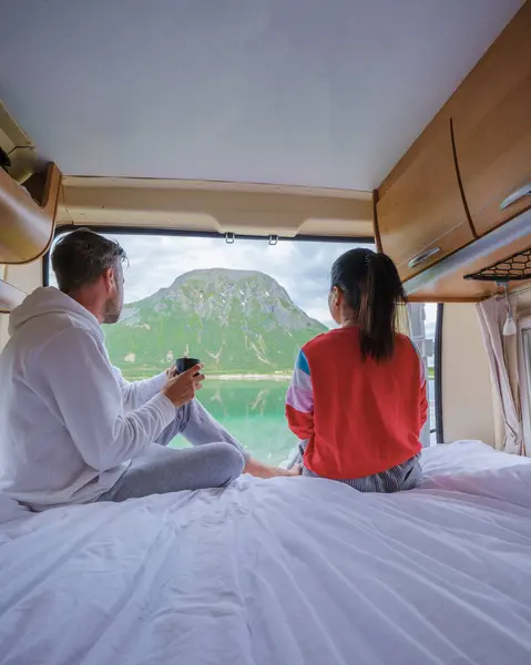 stock image A couple enjoys a mountain view from their camper bed in Norway. a men and women in a camper van bed looking out the window at the Lofoten Norway