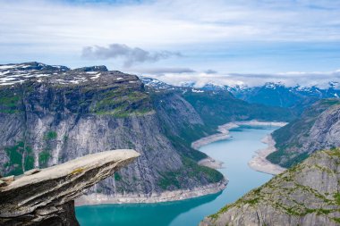 Norveç, Trolltunga 'nın kıyısından güzel bir manzara Norveç' in sarmal fiyorduna bakan bir uçurum. Dağlar, karla kaplı olan mesafeye kadar uzanıyor..