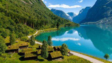 Çimen çatıları olan geleneksel Norveç kulübeleri, yemyeşil dağlar ve parlak mavi gökyüzü ile çevrili sakin bir fiyortla çevrili. Lovatnet Gölü Lodal Vadisi Norveç