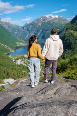 Birbirine kenetlenmiş, elleri kenetlenmiş, nefes kesici bir Norveç fiyorduna bakan bir çift. Uçsuz bucaksız, mavi gölü olan yeşil vadi önlerinde uzanır. Geiranger Fjord Norveç