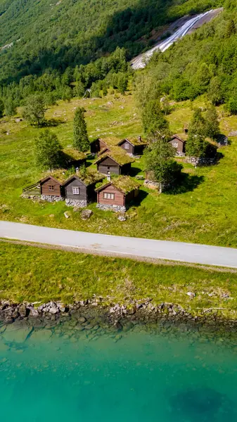 Çimen çatıları yemyeşil tepelerin arasına kurulmuş geleneksel ahşap kulübelerin sergilendiği küçük bir Norveç köyünün hava manzarası. Lovatnet Gölü Lodal Vadisi Norveç