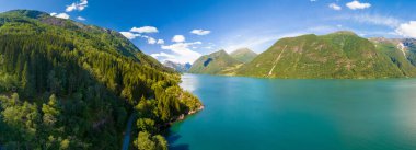 Norveç fiyordunun nefes kesici hava manzarası, yemyeşil dağlar, kristal berraklığında bir göl ve mavi gökyüzünde beyaz bulutlar. Fjaerlandsfjorden, Fjord, Vestland, Norveç
