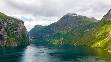 Norveç 'te yeşil yamaçları ve camsı zümrüt su yüzeyi olan sakin bir fiyort manzarası. Lovatnet Gölü Lodal Vadisi Norveç