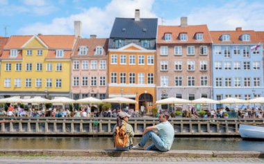 Bir çift Kopenhag 'da kanal kenarında oturmuş renkli binaların ve şehrin hareketli atmosferinin keyfini çıkarıyorlar. Kopenhag Danimarka