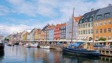 Kopenhag Danimarka 21 Temmuz 2024, Kopenhag, Danimarka 'da parlak renkli binaların canlı bir görüntüsü, tekneler kıyıya yanaşmış ve güneşli günün tadını çıkarıyorlar..