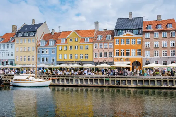 stock image Copenhagen Denmark 21 July 2024, A sunny day in Copenhagen with a cafe bustling with people enjoying the view of the canal and the colorful buildings.