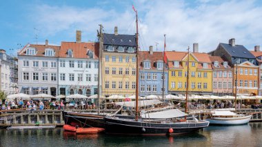 Kopenhag Danimarka 21 Temmuz 2024, Kopenhag 'da teknelerin yanaştığı ve insanların güneşin tadını çıkardığı renkli binaların manzarası..