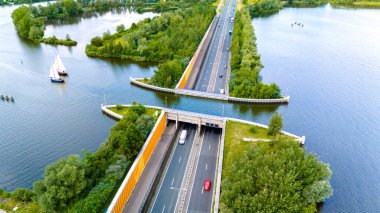 Hollanda 'daki Aquaduct Veluwemeer' in havadan görünüşü, tekneler altından geçerken arabaların kanaldan geçmesine izin veren yenilikçi mühendisliği gözler önüne seriyor. Yeşillik suların sınırında..