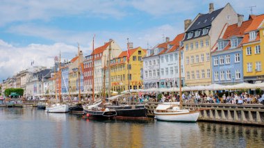 Kopenhag Danimarka 21 Temmuz 2024, Kopenhag, Danimarka 'da güneşli bir gün, liman boyunca tekneler yanaştı. Renkli binalar ve hareketli atmosfer resim gibi bir manzara yaratıyor..