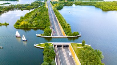 Hollanda 'daki Aquaduct Veluwemeer' in havadan görünüşü, işlek bir otoyolun üzerinde huzur içinde süzülen yelkenliler. Bir otoyolun üstündeki su kanalı.