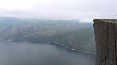 Dağların arasına kurulmuş bir göl ve uçurumun kenarında duran bir insan. Macera ve açık hava teması için mükemmel. Doğanın huzurunu yakalamak için. Norveç 'in huzuru.