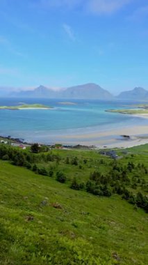 Hava görüntüleri, su, sahil, yeşil tarlalar, göller ve dağların doğal güzelliklerini yakalar. Huzur ve merak uyandıran sakin manzaralar yaratır, Lofoten Norveç.