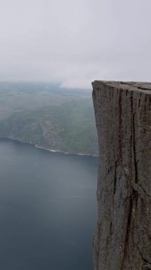 Huzurlu sulara tepeden bakan bir uçurumun yer aldığı, doğanın güzelliğini gözler önüne seren, Preikestolen Norveç 'teki bir gölün nefes kesici hava görüntüsü.