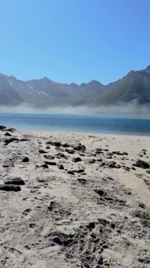 Dağları ve huzurlu bir gölü olan sakin bir sahil videosu, bir insanın doğal manzaranın ortasındaki huzurlu manzaranın tadını çıkarırken huzur ve güzelliği yakalar, Lofoten Norveç.