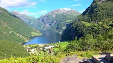 Görkemli dağları ve yemyeşil ağaçları olan bir vadideki gölün nefes kesici videosu. Huzurlu manzara, videodaki yaratıcı unsurlar olan Geiranger Fjord Norveç tarafından geliştirilmiştir.