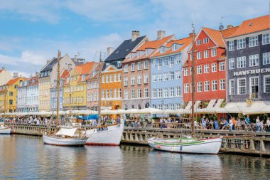 Kopenhag Danimarka 21 Temmuz 2024, Kopenhag, Danimarka 'daki Nyhavn Kanalı rıhtıma yanaşmış renkli binalar, tekneler ve güneşli havanın ve hareketli atmosferin keyfini çıkaran insanlar yer almaktadır.