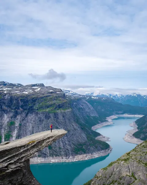 stock image A hiker stands on the edge of the Trolltunga cliff in Norway, overlooking a vast and scenic fjord. Asian women hiking the Trolltunga, Norway