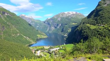 Bir video, yüksek dağlarla çevrili sakin bir dağ vadisini gösteriyor. Sakin göl görkemli manzarayı yansıtıyor, nefes kesici bir manzara sunuyor, Geiranger Fjord Norveç