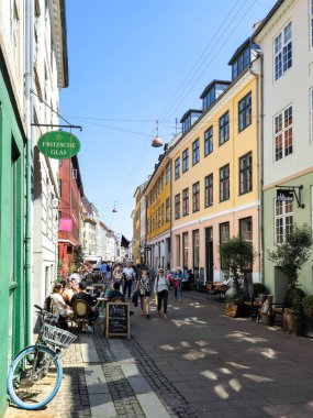 Kopenhag Danimarka 21 Temmuz 2024, Kopenhag 'da hareketli bir cadde turistler açık mavi gökyüzü altındaki renkli binaları, kafeleri ve yerel dükkanları keşfederken hareketleniyor..