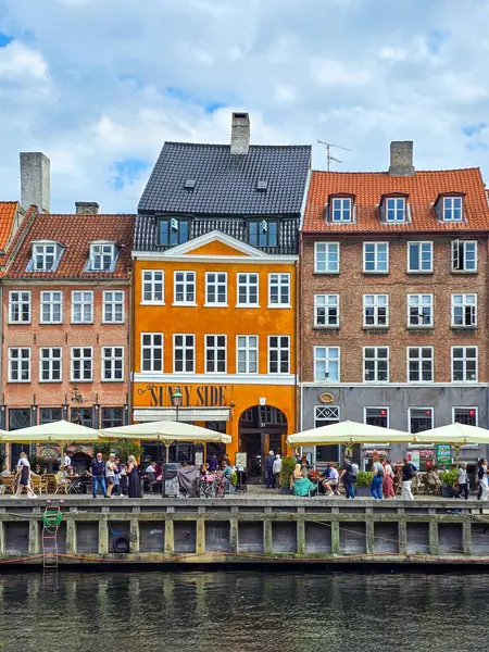 stock image Copenhagen Nyhavn Canal Denmark 21 July 2024, Vibrant cafes and cheerful patrons line the canal's edge, basking in the warm sunlight of a beautiful day 