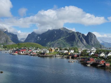 Lofoten Adaları 'nın nefes kesici manzarası parlak bir gökyüzünün altında yükselen dağlara karşı yuva yapmış renkli deniz manzaralı evleri ortaya çıkarıyor. Lofoten Norveç 