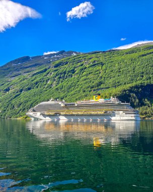 Geiranger fjord Norveç 10 Temmuz 2024, muazzam bir yolcu gemisi Norveç fiyortlarının sakin sularında zarif bir şekilde yelken açar, yemyeşil dağlar ve berrak gökyüzü ile çevrilidir..