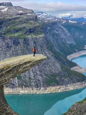 Yalnız bir maceraperest, Norveç 'teki nefes kesen fiyort sularına ve engebeli dağlara tepeden bakan doğal bir kaya çıkıntısı üzerinde durmaktadır. Trolltunga, Norveç