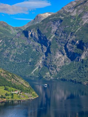 Berrak mavi gökyüzünün altında, yüksek uçurumlar ve yemyeşil yemyeşil ile çevrili serin bir tekne, çarpıcı fiyortta süzülüyor. Norveç 'in Geiranger' si 