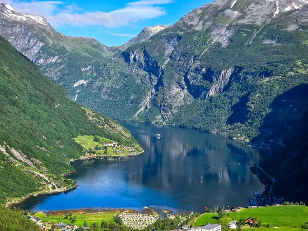 Sakin bir fiyort, sakin sularda süzülen bir kayığın Norveç 'in çarpıcı doğal güzelliğini sergilemesiyle yemyeşil dağları yansıtıyor. Norveç 'in Geiranger' si