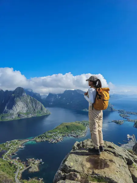 stock image A traveler stands atop a rocky outcrop, admiring the stunning fjords and islands of Lofoten, bathed in sunlight. Reinebringen Lofoten Norway 